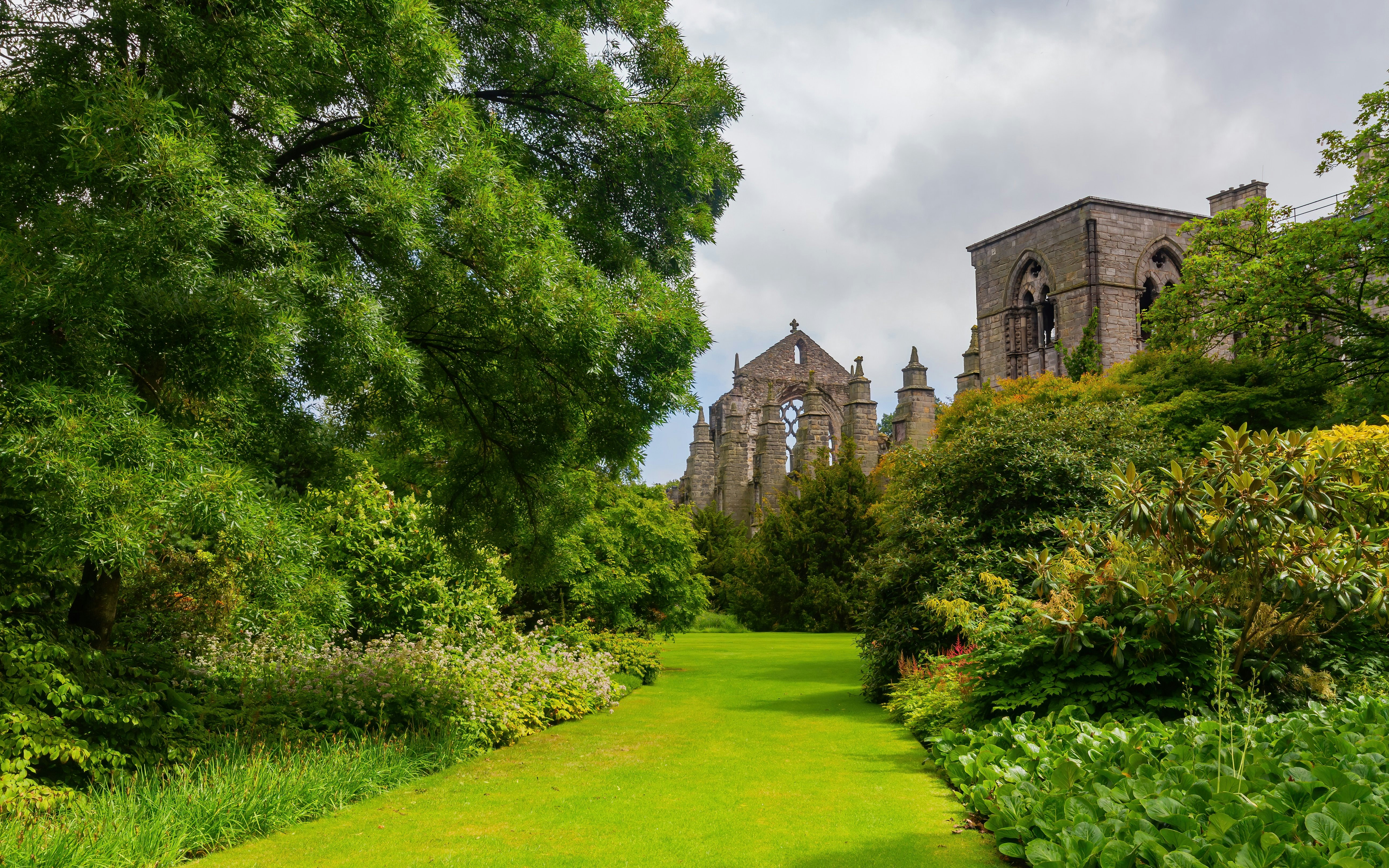 Holyroodhouse gardens with lush greenery and historic abbey ruins in the background.