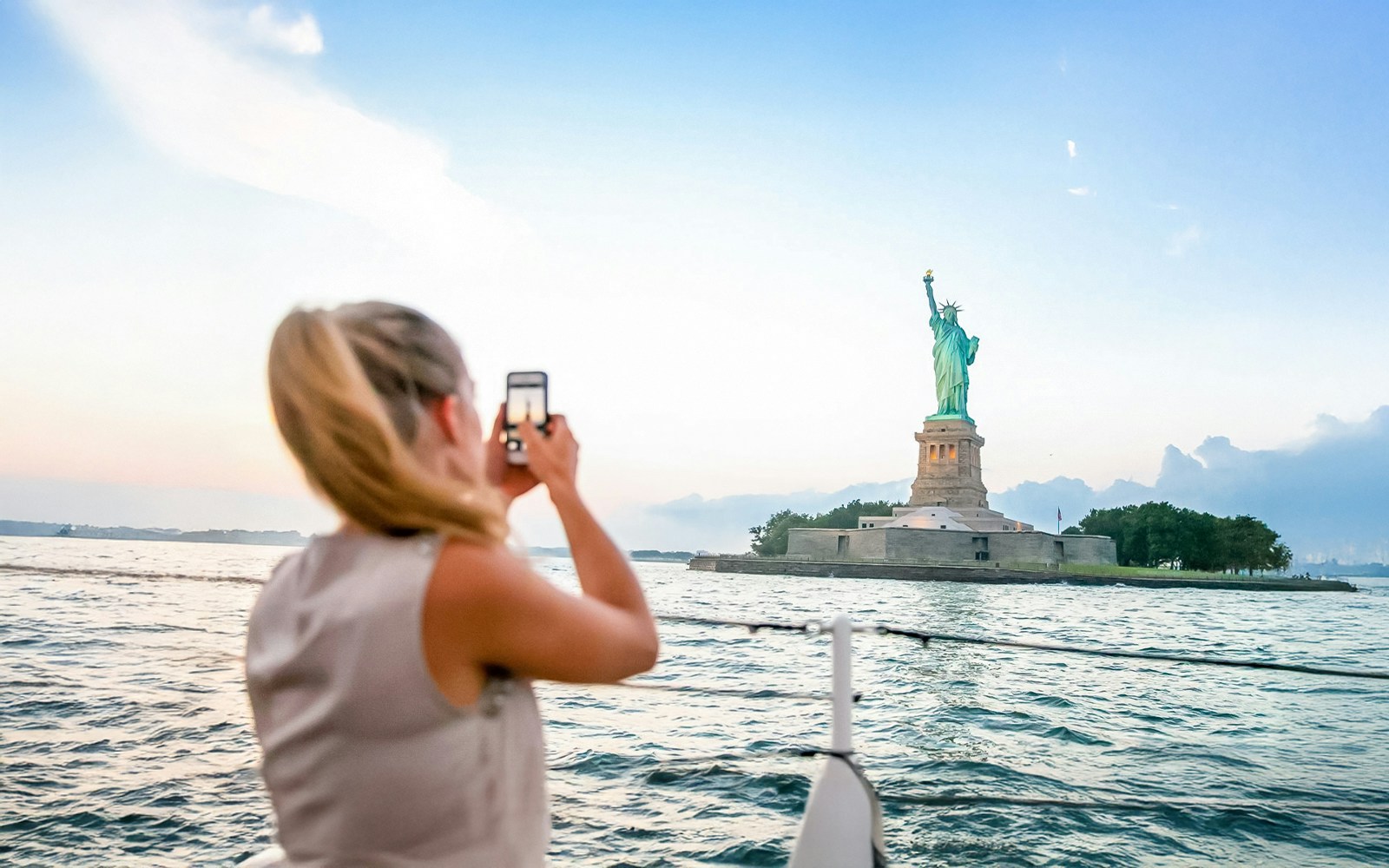 Woman on 60 Mins Lady Liberty Cruise with Statue of Liberty in background, New York City.