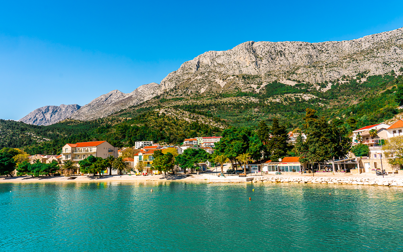 Drvenik town coastline with mountains in the background seen from a ferry.