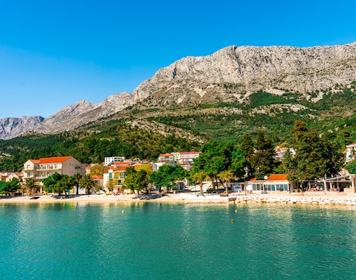 Drvenik town coastline with mountains in the background seen from a ferry.