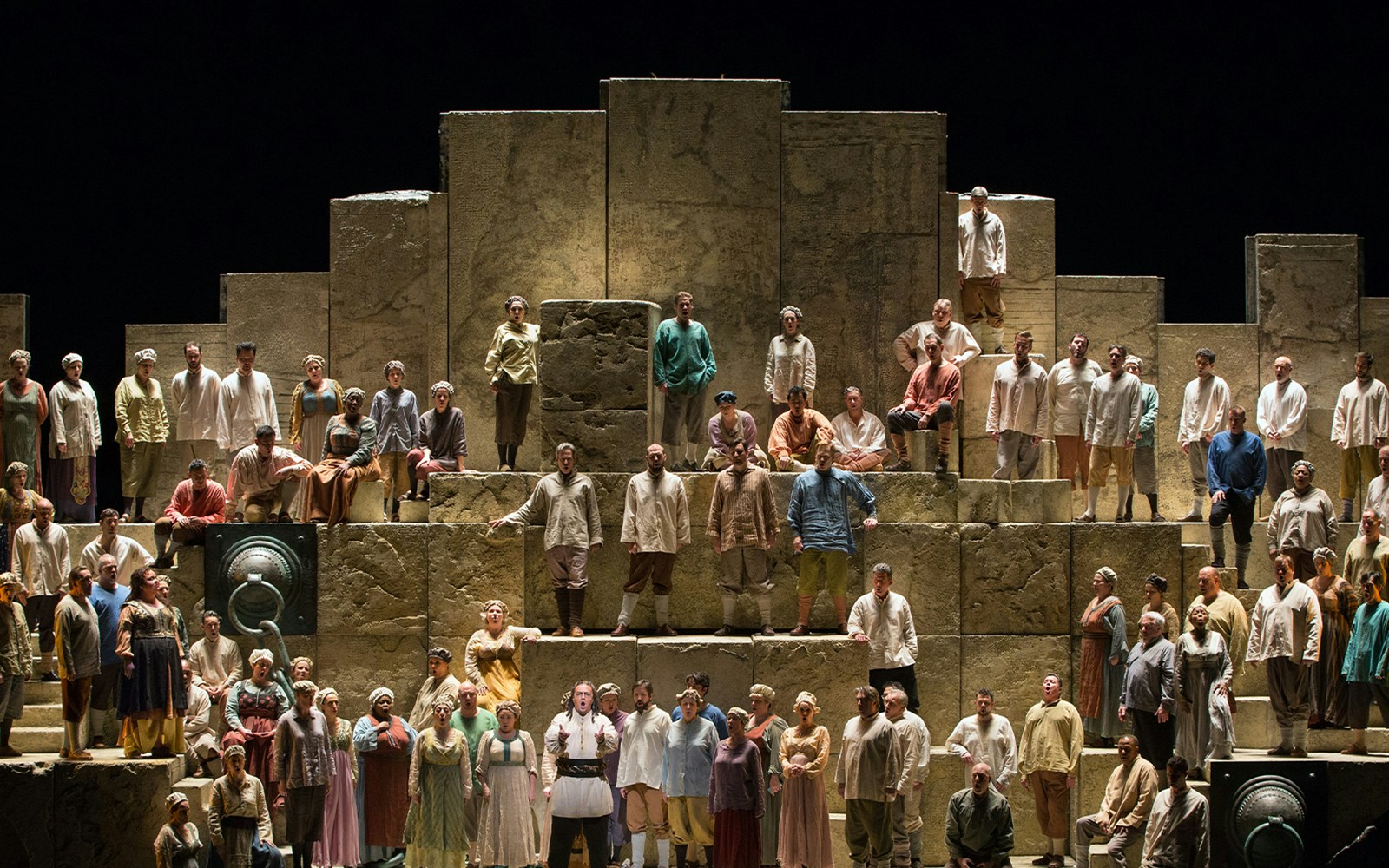 Opera performers on stage during a production of Nabucco, featuring a large ensemble cast.