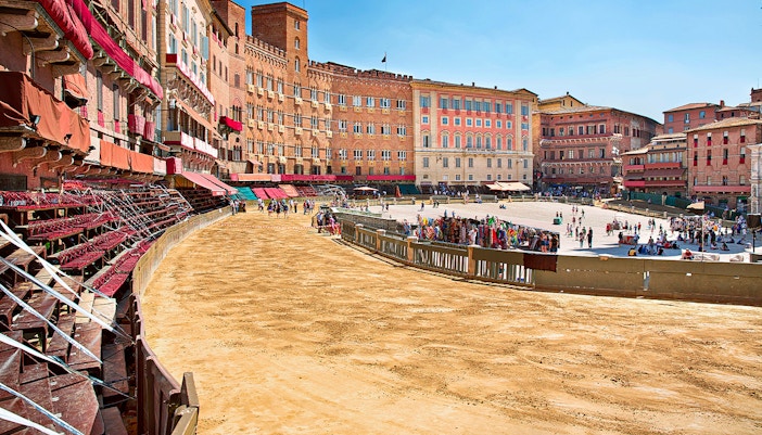 Siena's Piazza del Campo prepared for the Palio horse race with spectators gathering.
