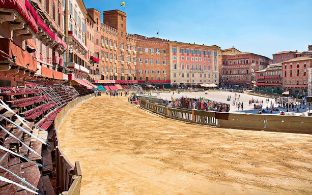 Siena's Piazza del Campo prepared for the Palio horse race with spectators gathering.