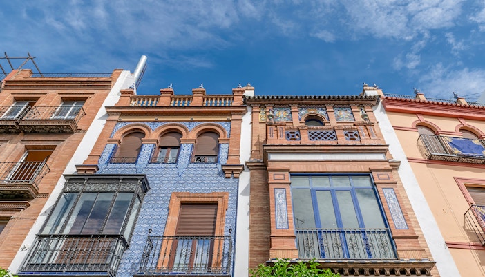 Colorful facades of historic buildings on Calle San Jacinto, Seville.