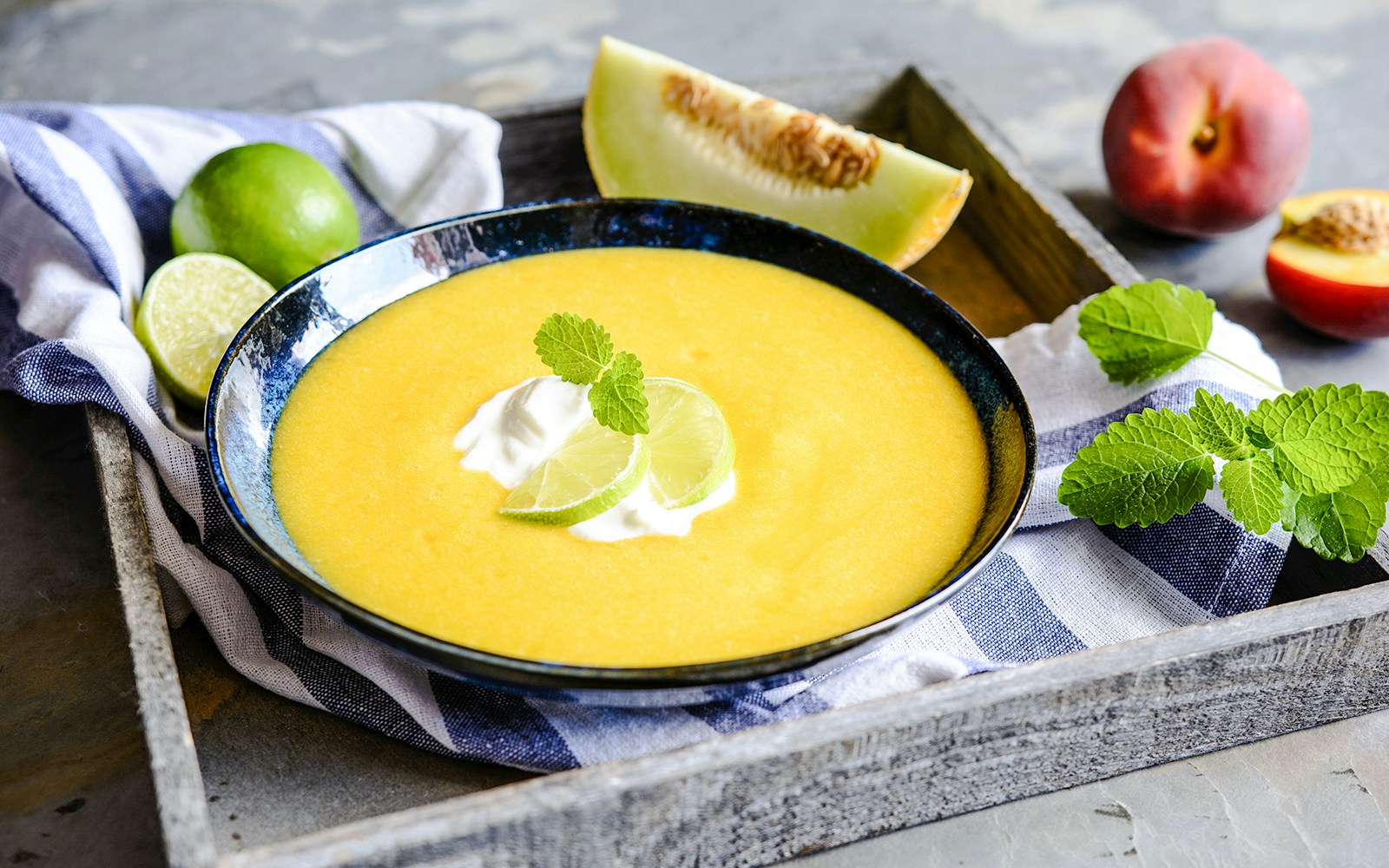 Chilled soupe de melon garnished with lime slices and mint leaves.