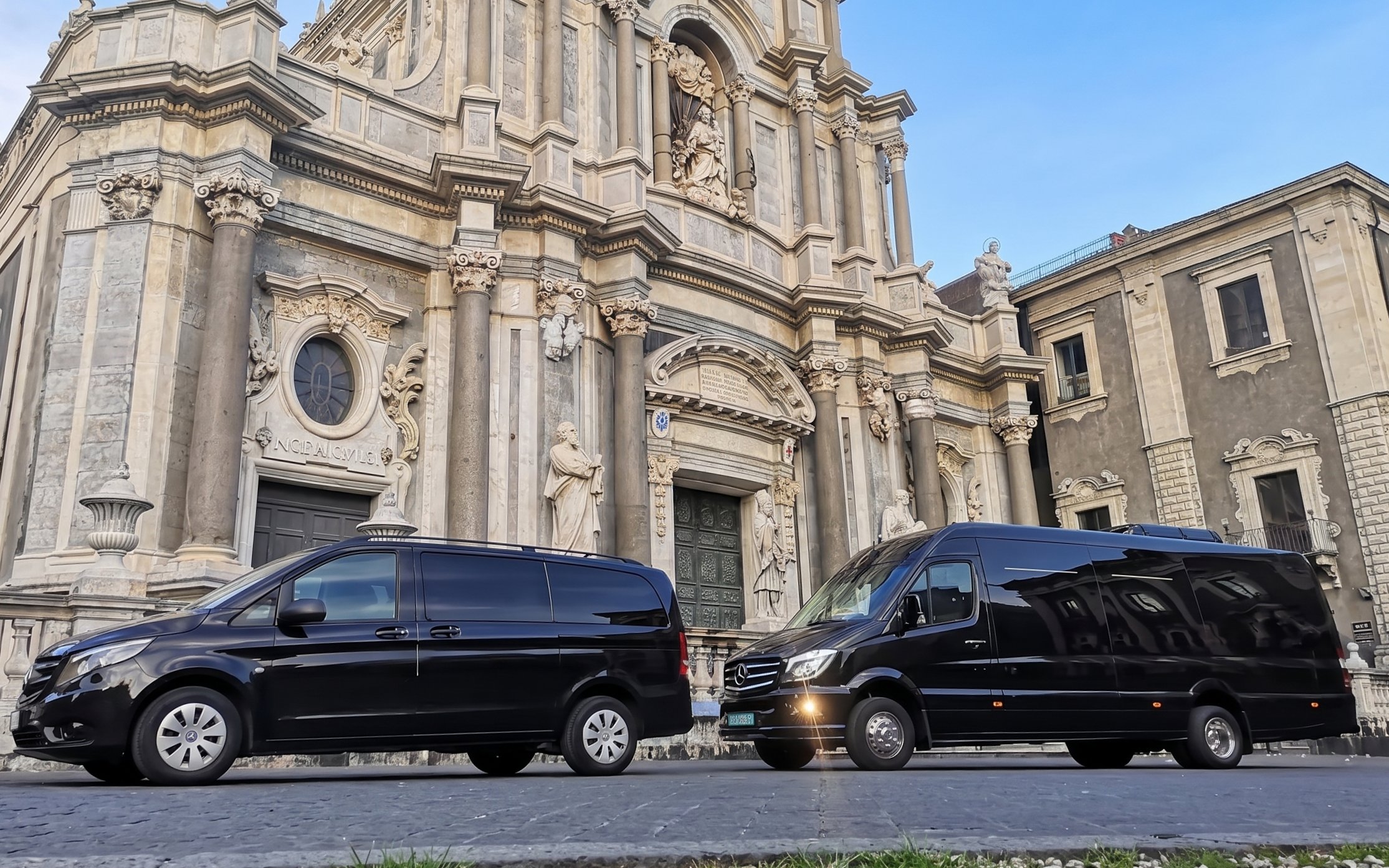 Black tour vans parked in front of a historic building in Agrigento, Piazza Armerina.