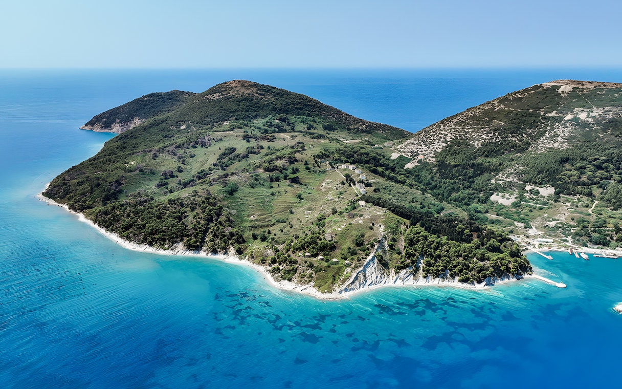 Aerial view of lush green peninsula with turquoise waters, part of Vlora's Ionian Odyssey, Albania.