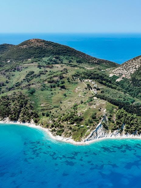 Aerial view of lush green peninsula with turquoise waters, part of Vlora's Ionian Odyssey, Albania.