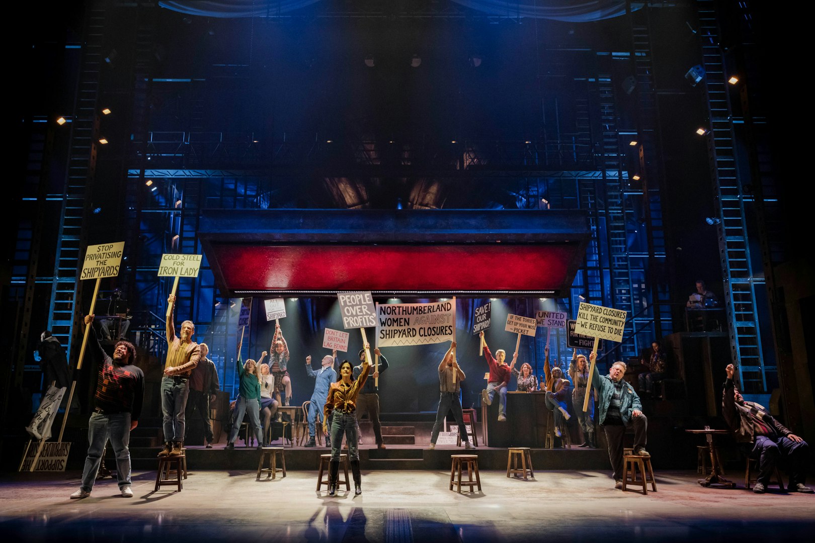 Stage performance of "The Last Ship" in Brisbane with actors holding protest signs.