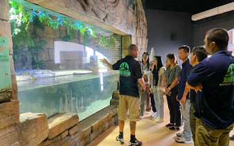 Group tour at Angkor Wildlife & Aquarium, guide explaining crocodile exhibit, Siem Reap.