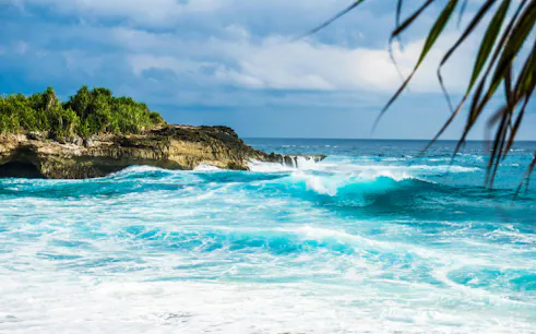 Nusa Lembongan coastline with waves crashing against rocky cliffs.