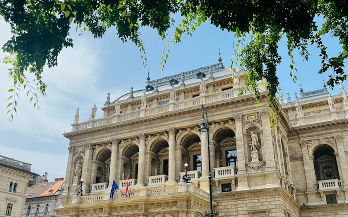 Hungarian State Opera House facade with statues and flags, Budapest.