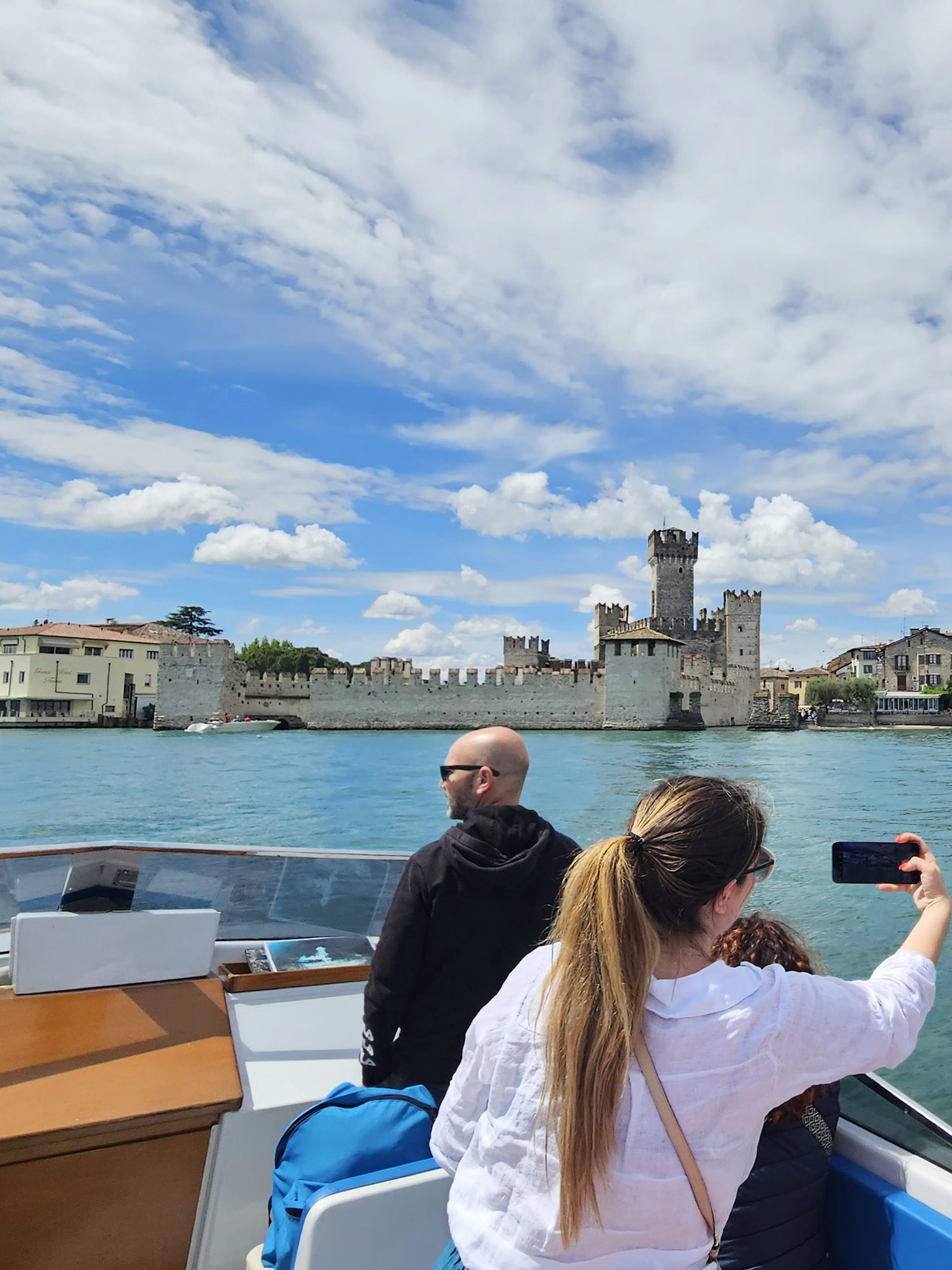 Private boat tour with people viewing Sirmione Castle on Lake Garda, Italy.