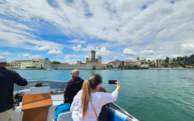 Private boat tour with people viewing Sirmione Castle on Lake Garda, Italy.