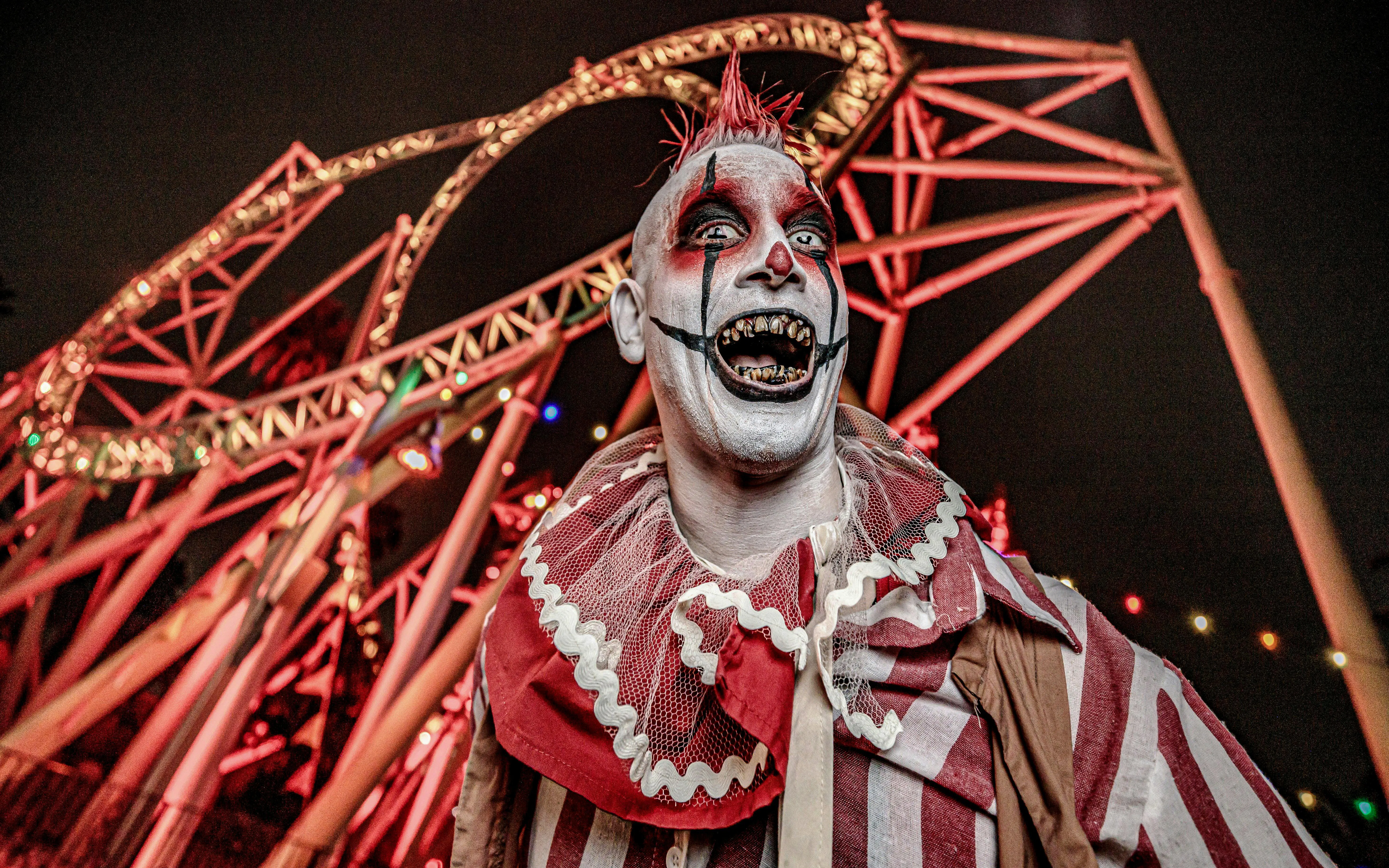 Clown in front of roller coaster at Knott's Berry Scary Farm, Southern California.