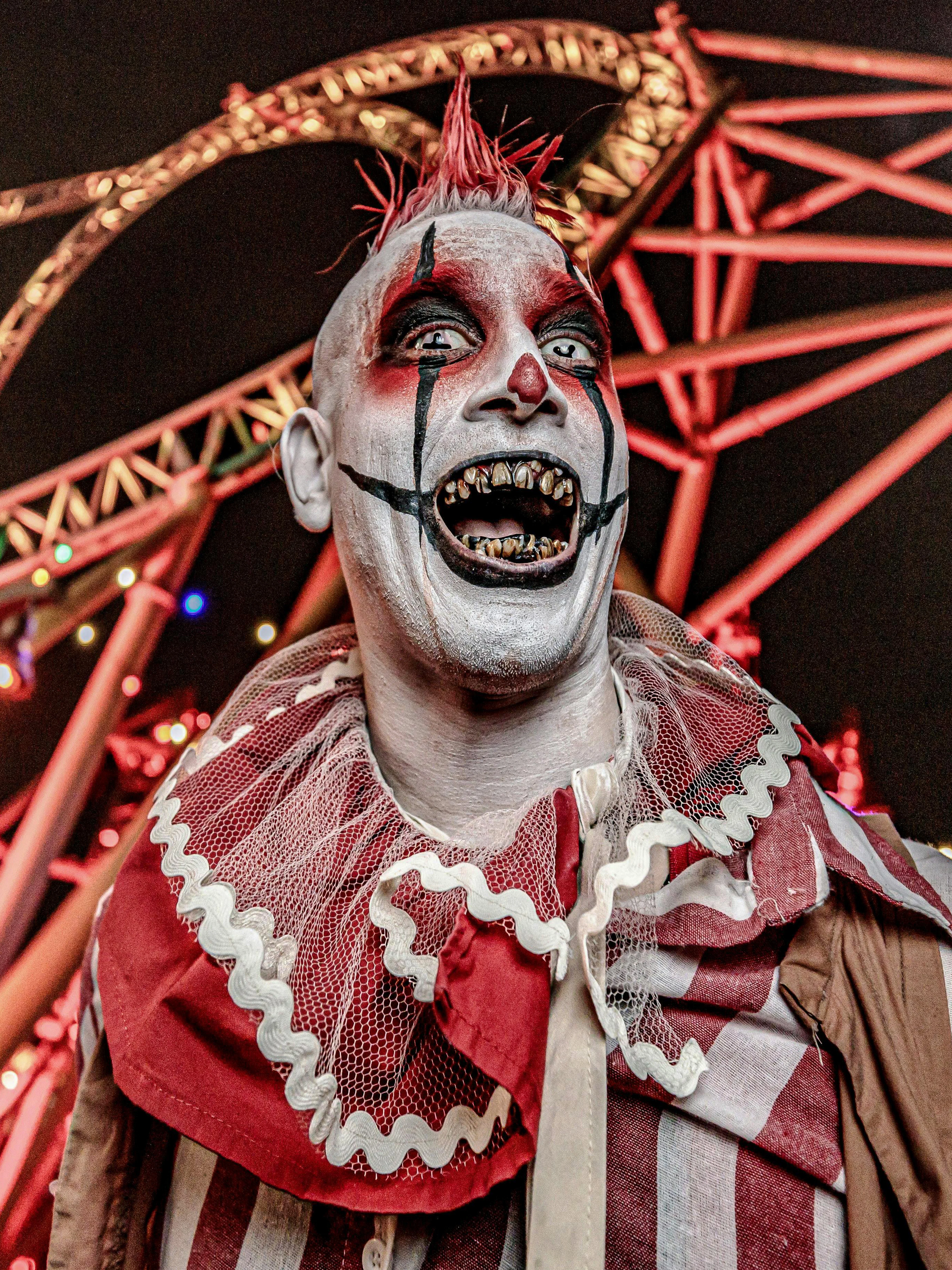 Clown in front of roller coaster at Knott's Berry Scary Farm, Southern California.