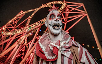 Clown in front of roller coaster at Knott's Berry Scary Farm, Southern California.