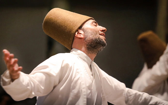 Whirling Dervish performing in traditional attire during a ceremony in Istanbul.