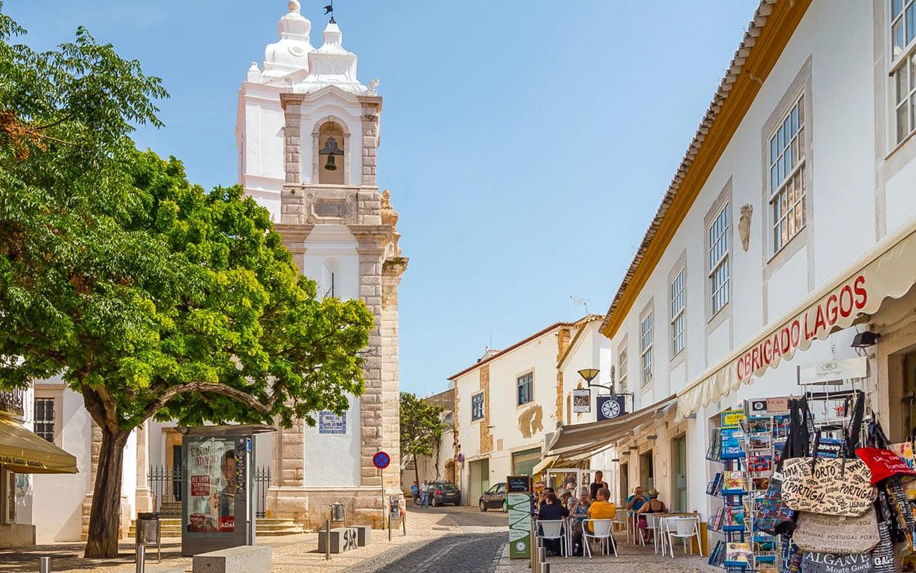 Historic street with bell tower and shops in Lagos, Western Algarve.
