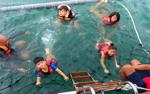 People swimming in the ocean with life vests during Dragon Sunset Cruise.