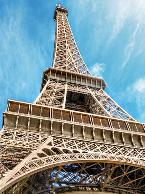 Eiffel Tower viewed from below against a blue sky in Paris, France.