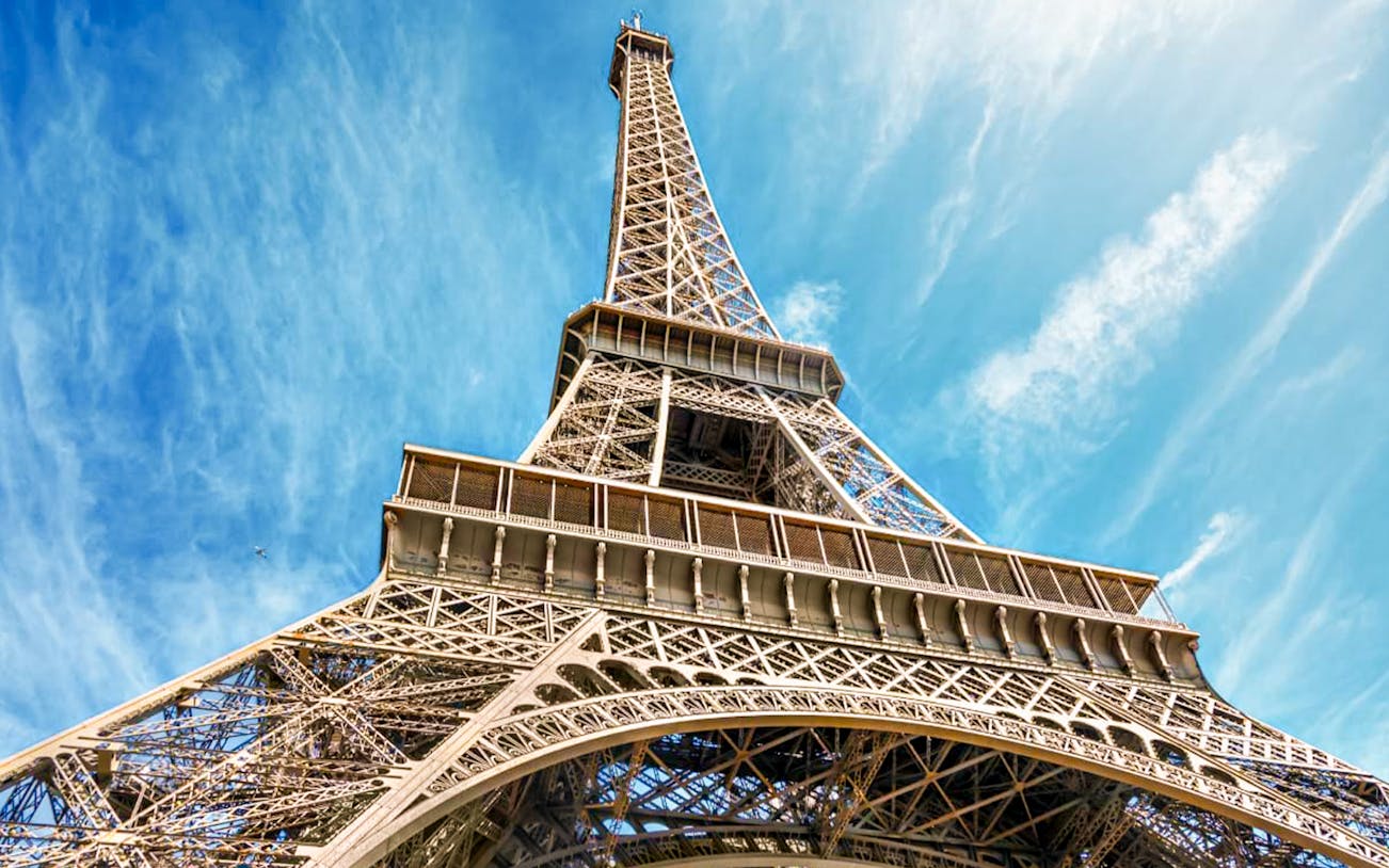 Eiffel Tower viewed from below against a blue sky in Paris, France.