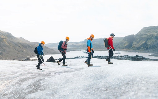 Guests hiking on Solheimajökill Glacier in Iceland with scenic mountain views.
