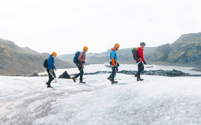 Guests hiking on Solheimajökill Glacier in Iceland with scenic mountain views.