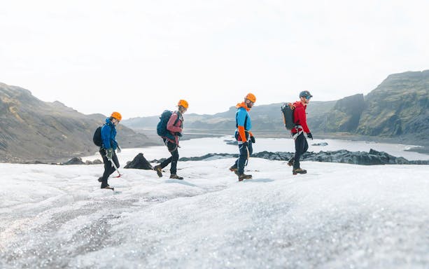 Guests hiking on Solheimajökill Glacier in Iceland with scenic mountain views.