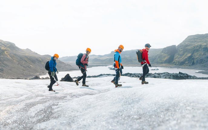 Guests hiking on Solheimajökill Glacier in Iceland with scenic mountain views.