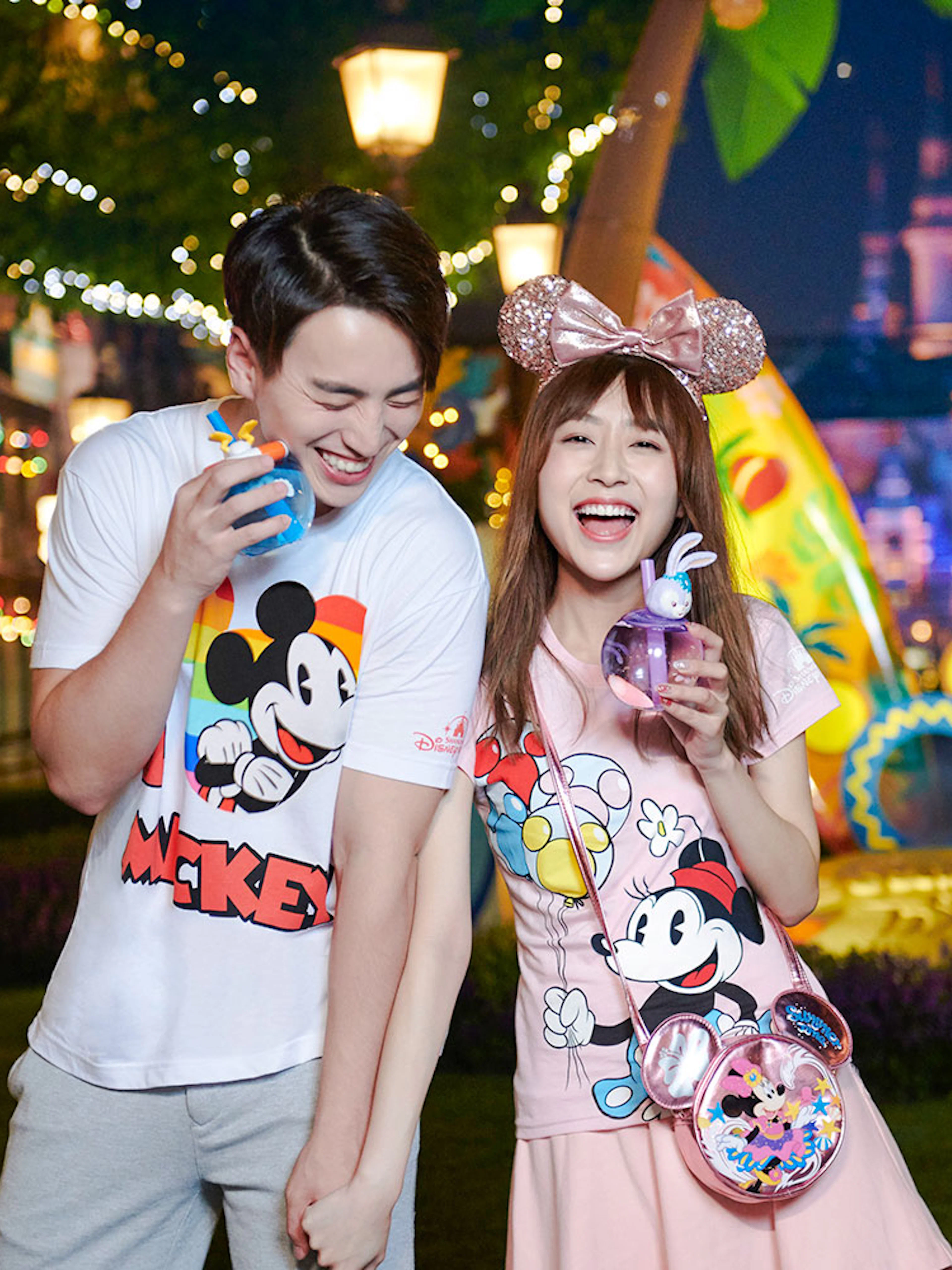 Couple enjoying nighttime at Shanghai Disneyland with Mickey Mouse merchandise.