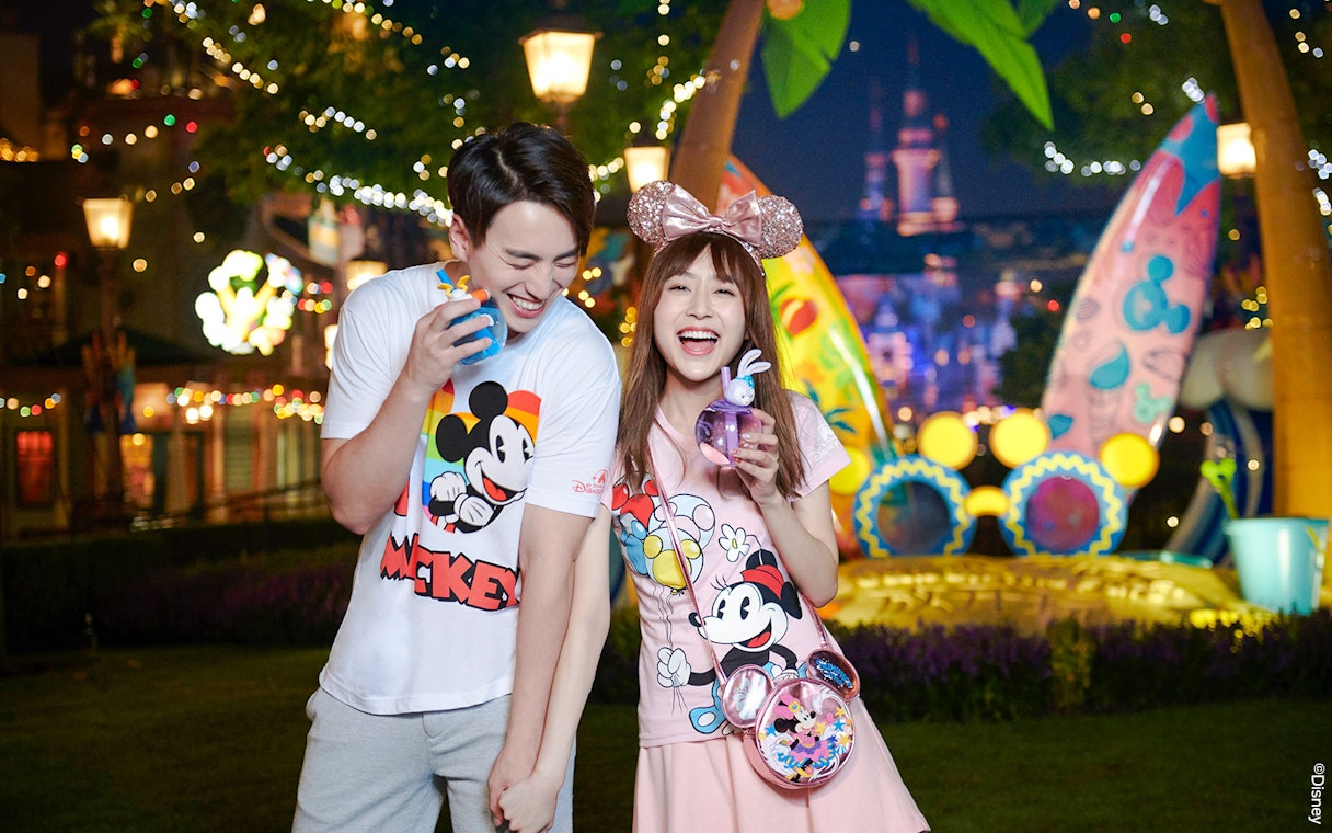 Couple enjoying nighttime at Shanghai Disneyland with Mickey Mouse merchandise.