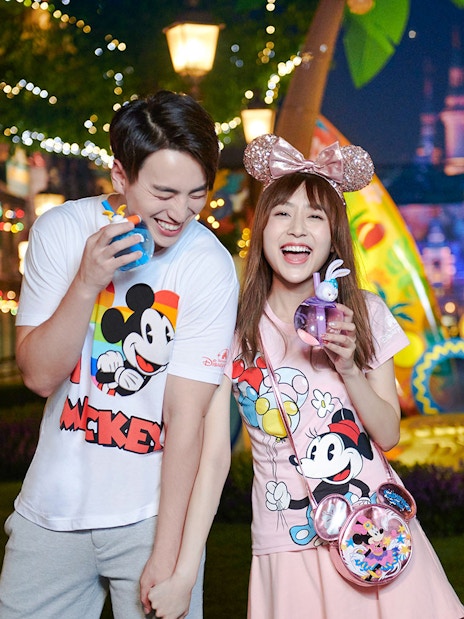 Couple enjoying nighttime at Shanghai Disneyland with Mickey Mouse merchandise.