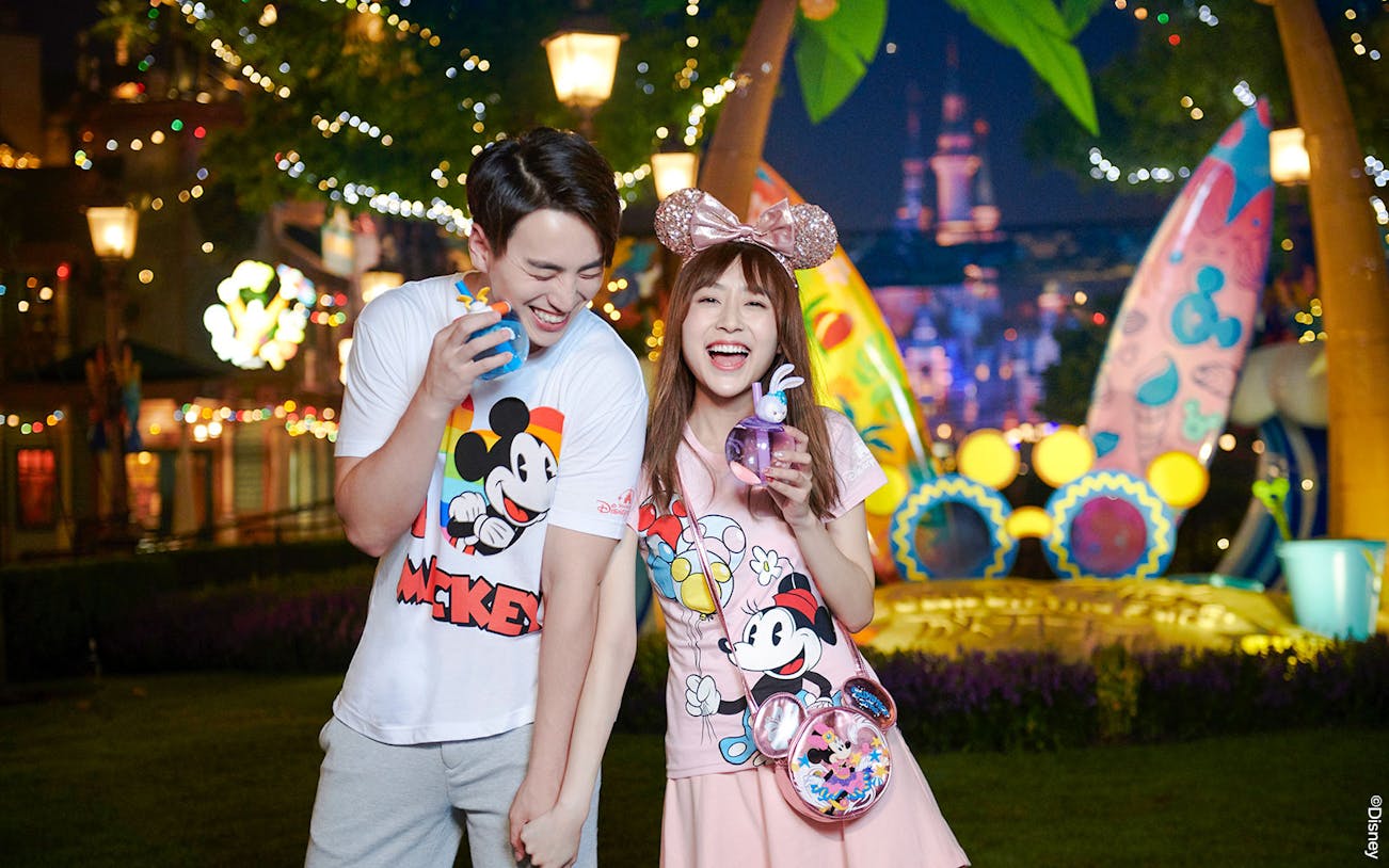 Couple enjoying nighttime at Shanghai Disneyland with Mickey Mouse merchandise.