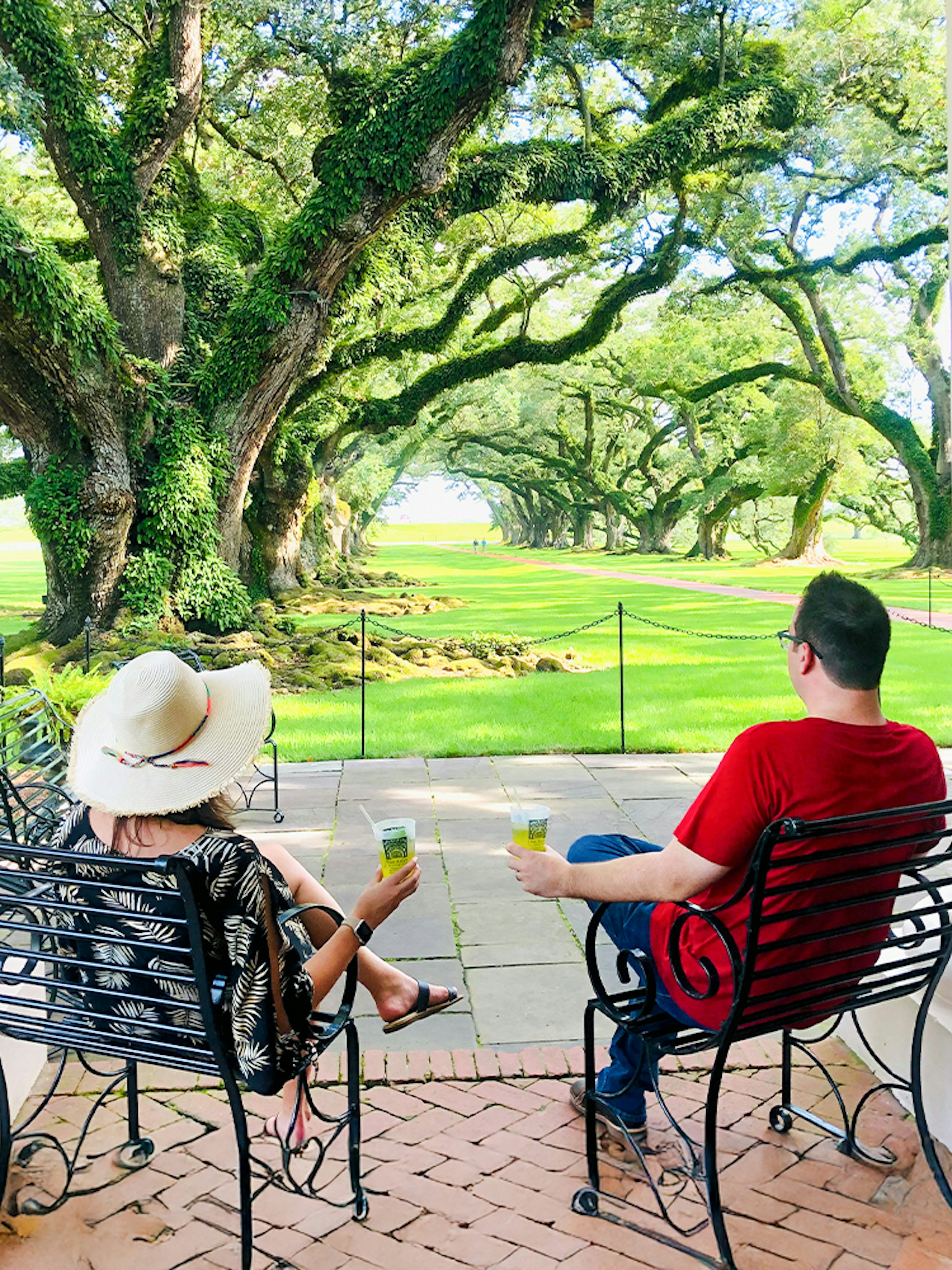 Visitors relaxing on a porch at Oak Alley Plantation, viewing the iconic oak trees.