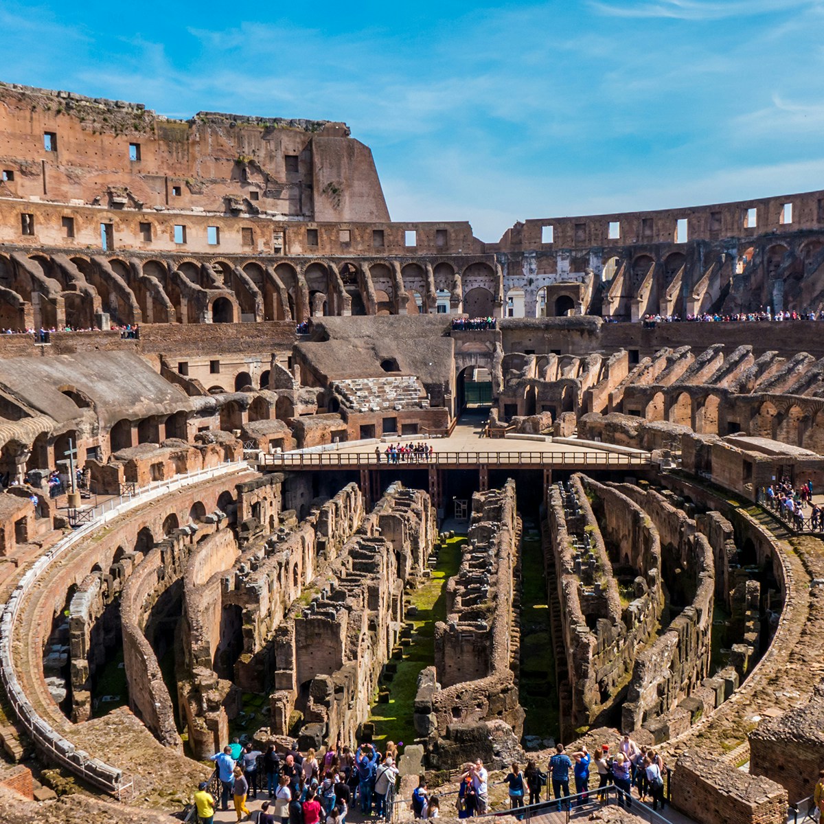 Colosseum interior with tourists exploring ancient Roman architecture in Rome, Italy.