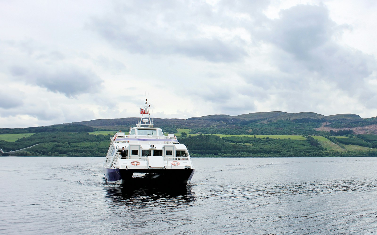 Cruise boat on Loch Ness with Scottish Highlands in the background.