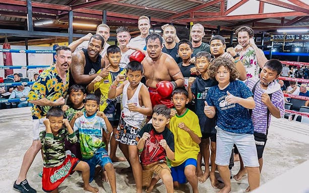 Group of people posing in a boxing ring at Rawai Muay Thai Boxing Camp.