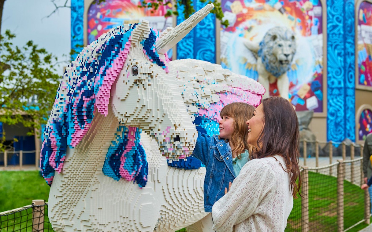 Child and adult admiring LEGO unicorn at LEGOLAND® Windsor Resort.