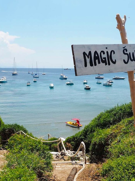 Pathway leading to Šunj Beach with boats anchored in the bay, Lopud Island, Croatia.
