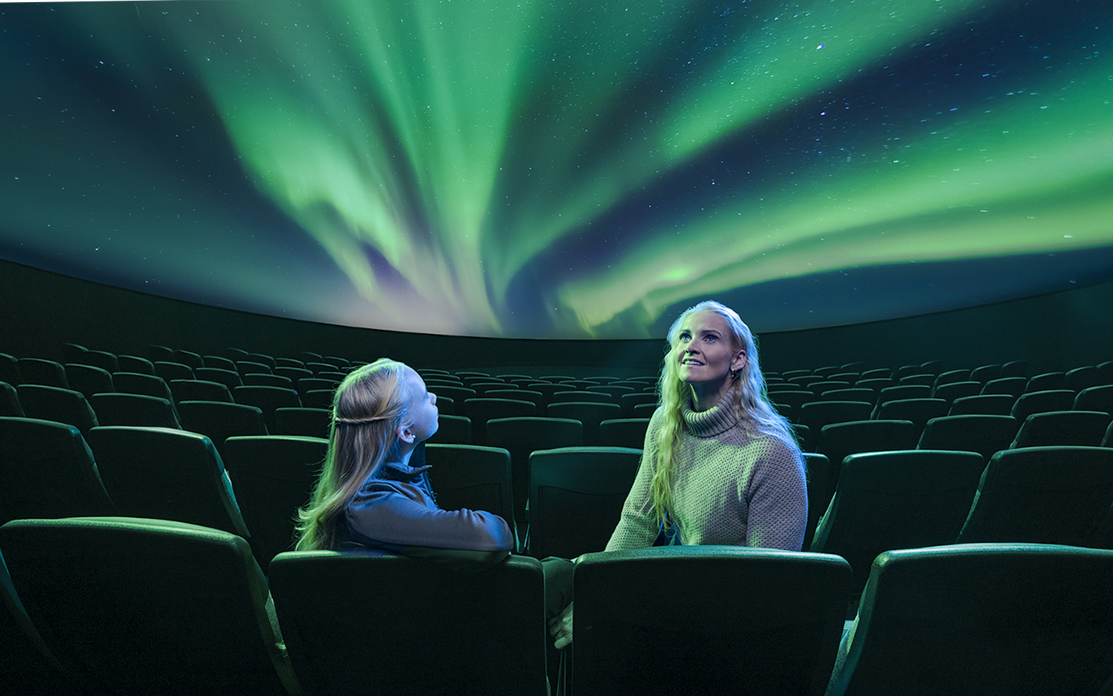 Visitors watching Áróra northern lights show at Perlan Museum planetarium.