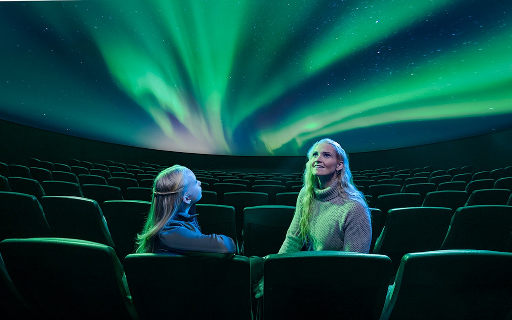 Visitors watching Áróra northern lights show at Perlan Museum planetarium.
