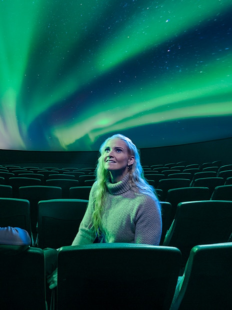 Visitors watching Áróra northern lights show at Perlan Museum planetarium.