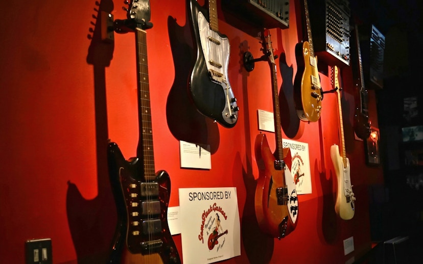 Guitars displayed on a red wall at the Irish Rock N Roll Museum Experience.