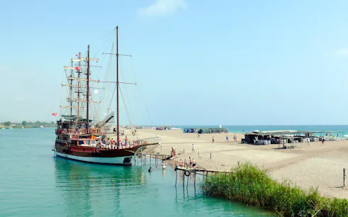 Cruise ship docked at sandy beach during Manavgat River to Dolphin Island tour.