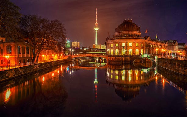 Berlin's Bode Museum and TV Tower illuminated at night along the Spree River.