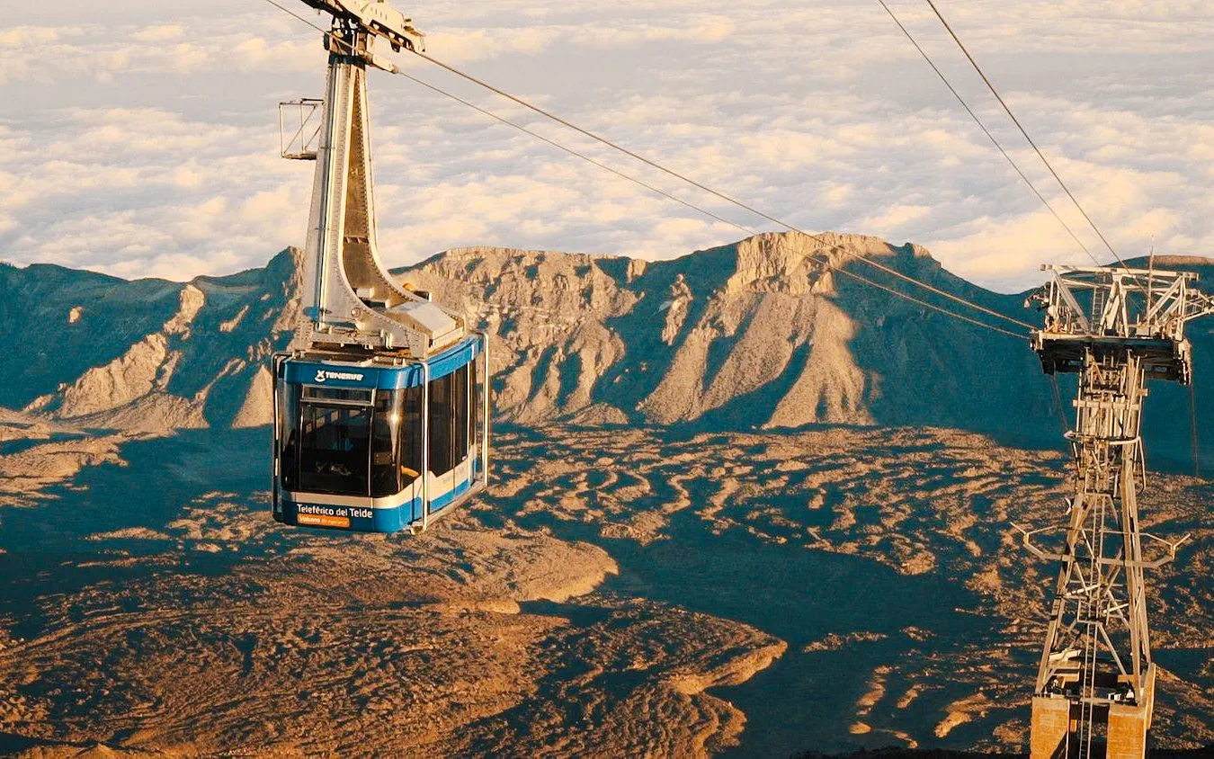 Cable car ascending Mount Teide with rocky landscape below.