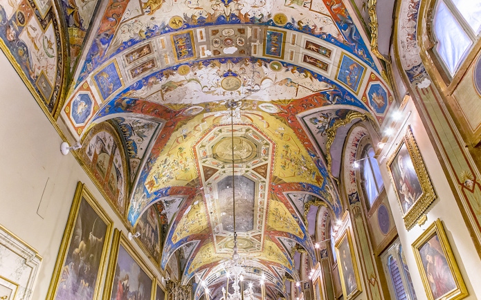 Doria Pamphilj Gallery ornate ceiling with vibrant frescoes and framed paintings.