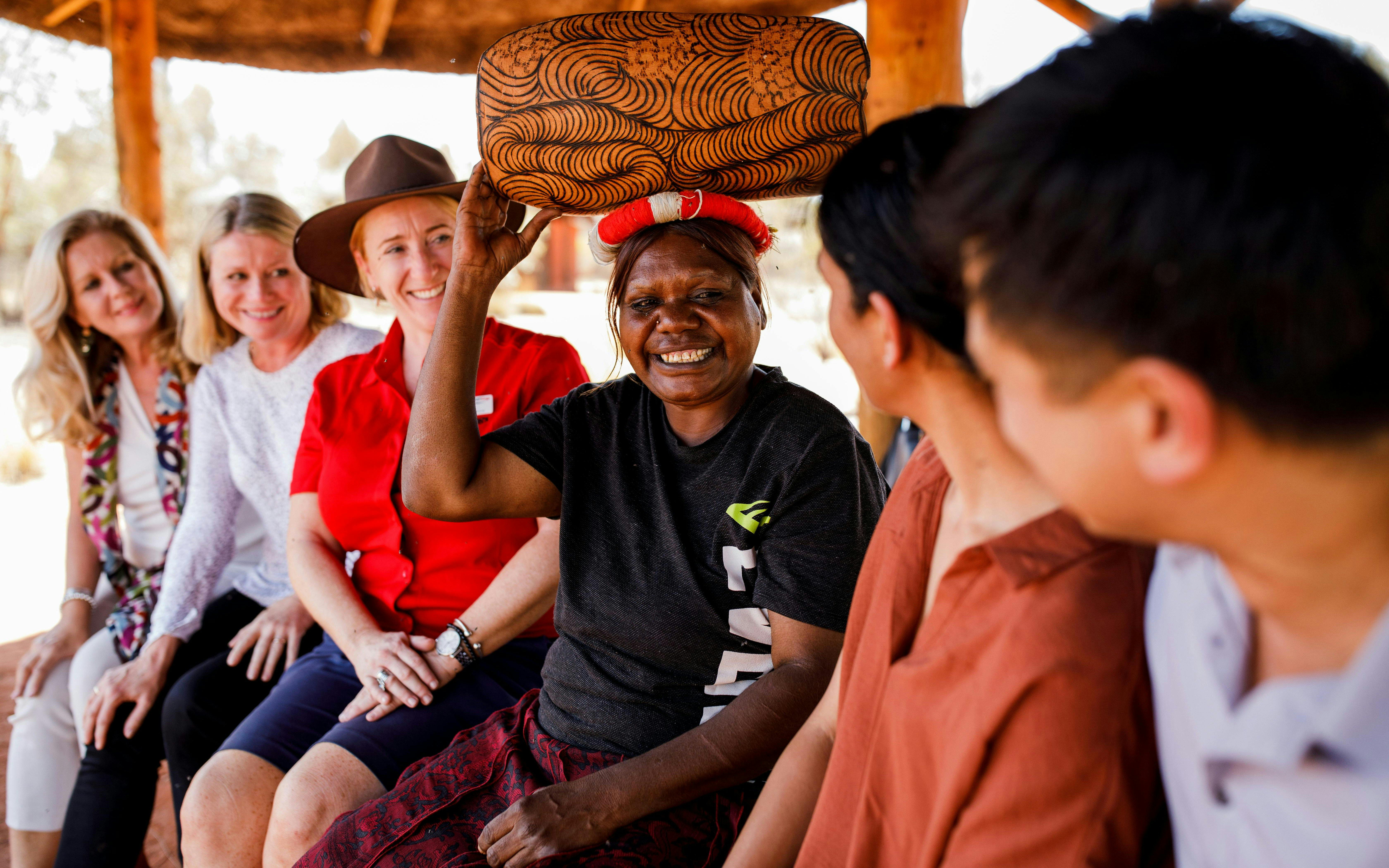 Aboriginal guide shares stories with tourists during Uluru sunrise tour.