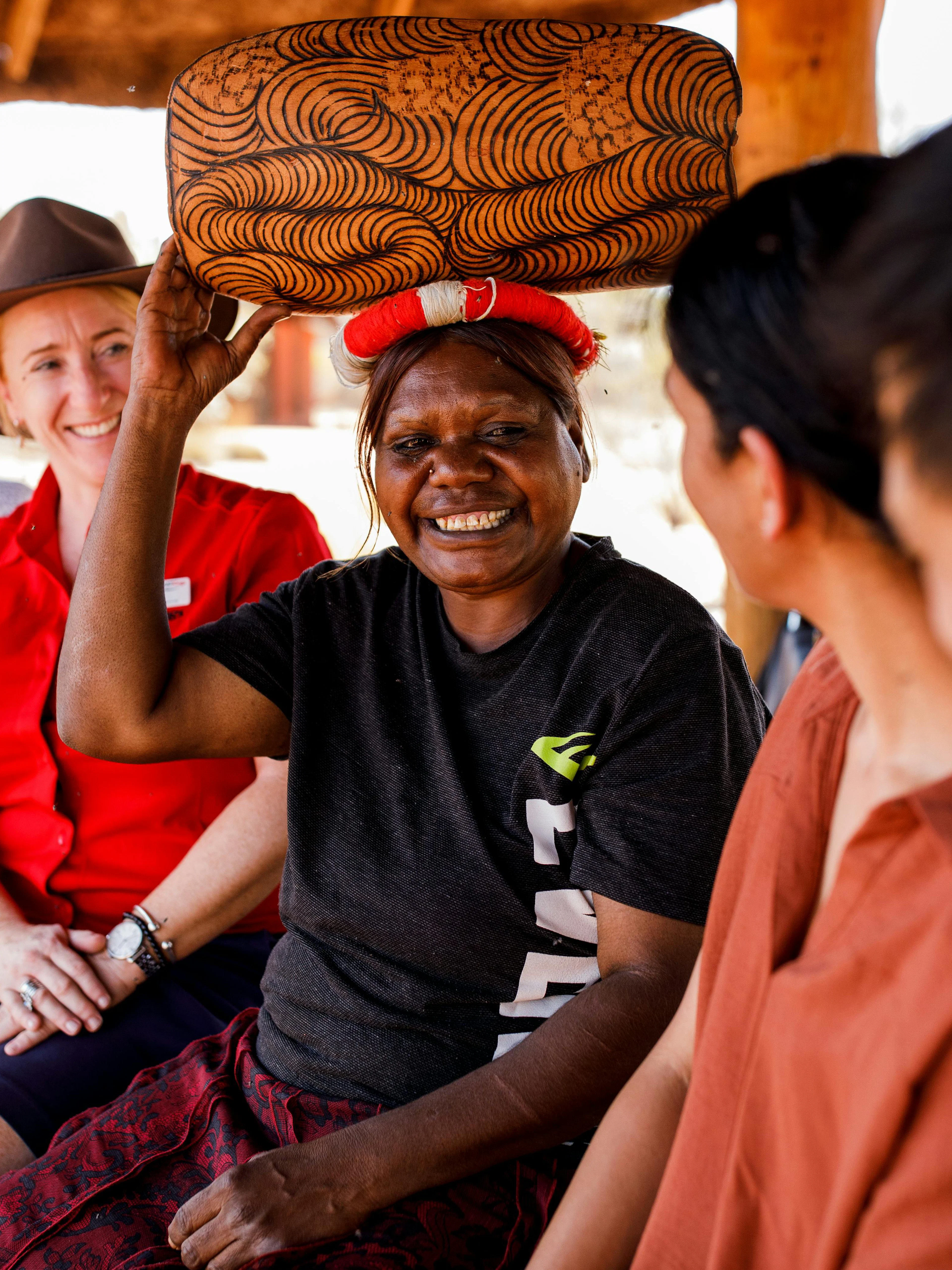 Aboriginal guide shares stories with tourists during Uluru sunrise tour.